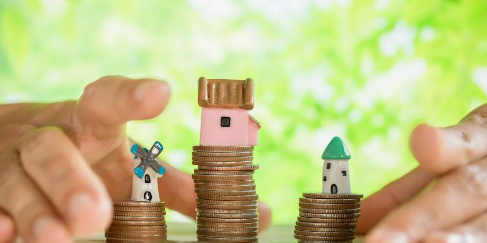 Graphic related to increasing property value. Minature homes stacked on coins.