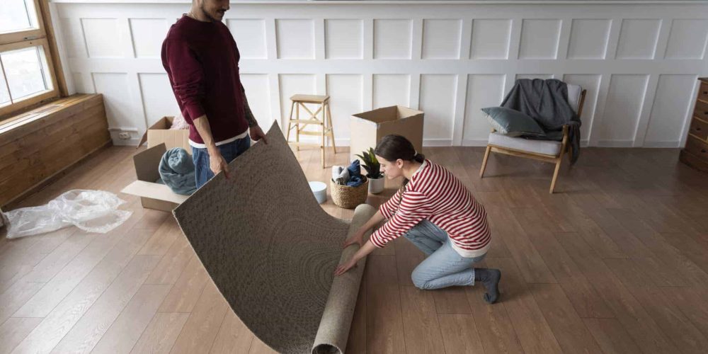 Couple unrolling a rug over hard wood floor