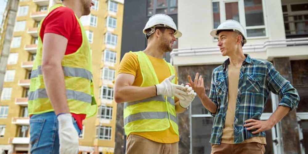 Contractors with hard hats having a conversation at a job site