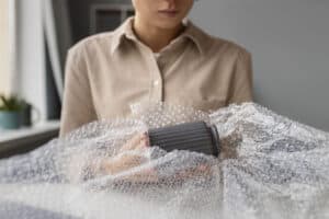 Woman packing fragile items with bubble wrap