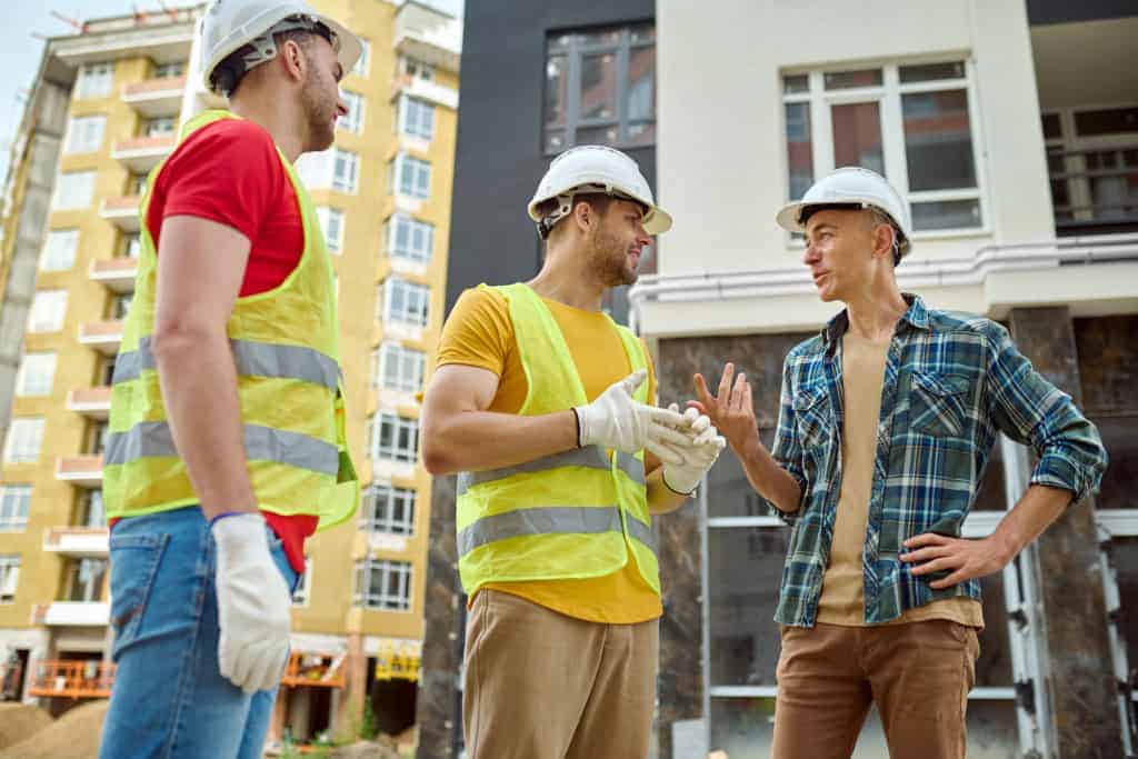 Contractors with hard hats having a conversation at a job site